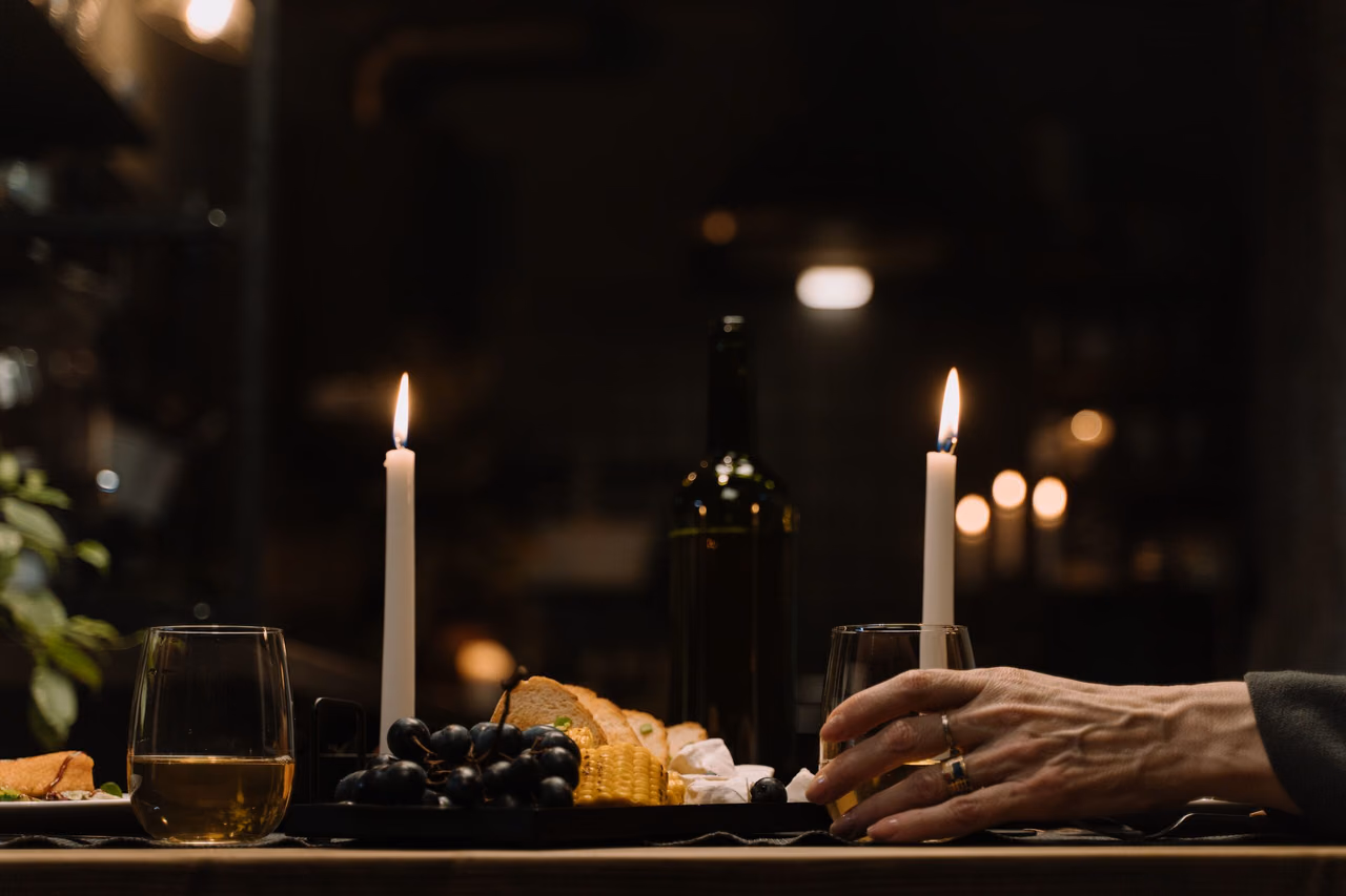Pahare de vin la lumina a două lumânări, pe o masă pregătită de seară